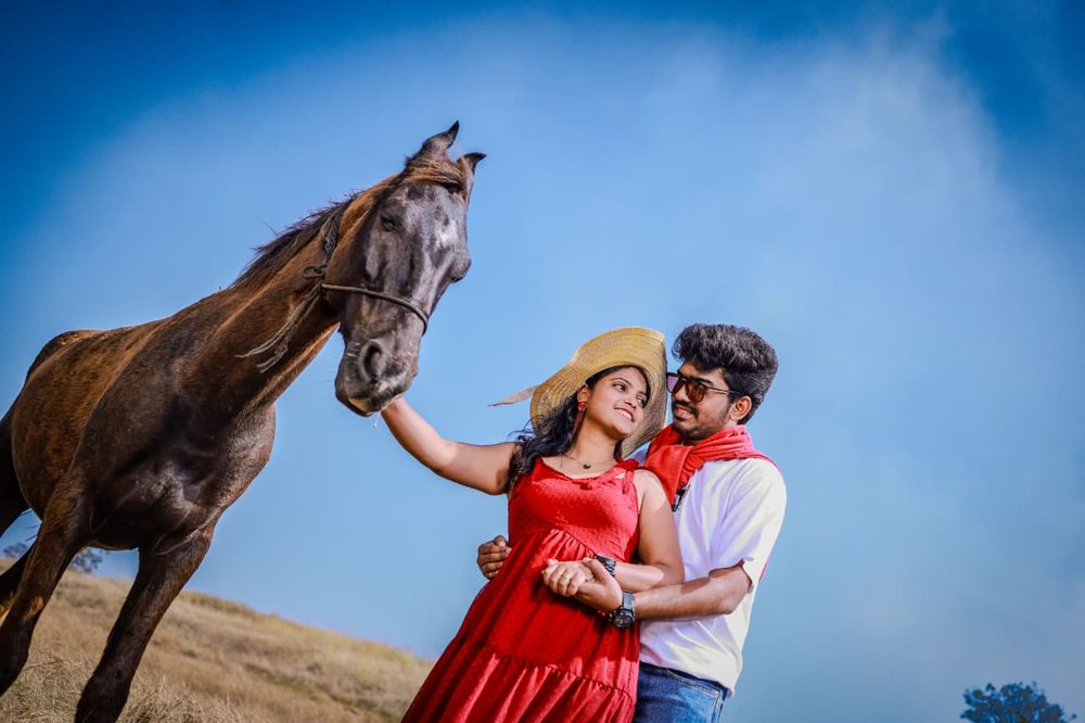 Pre-wedding couple portrait with a horse in an open field